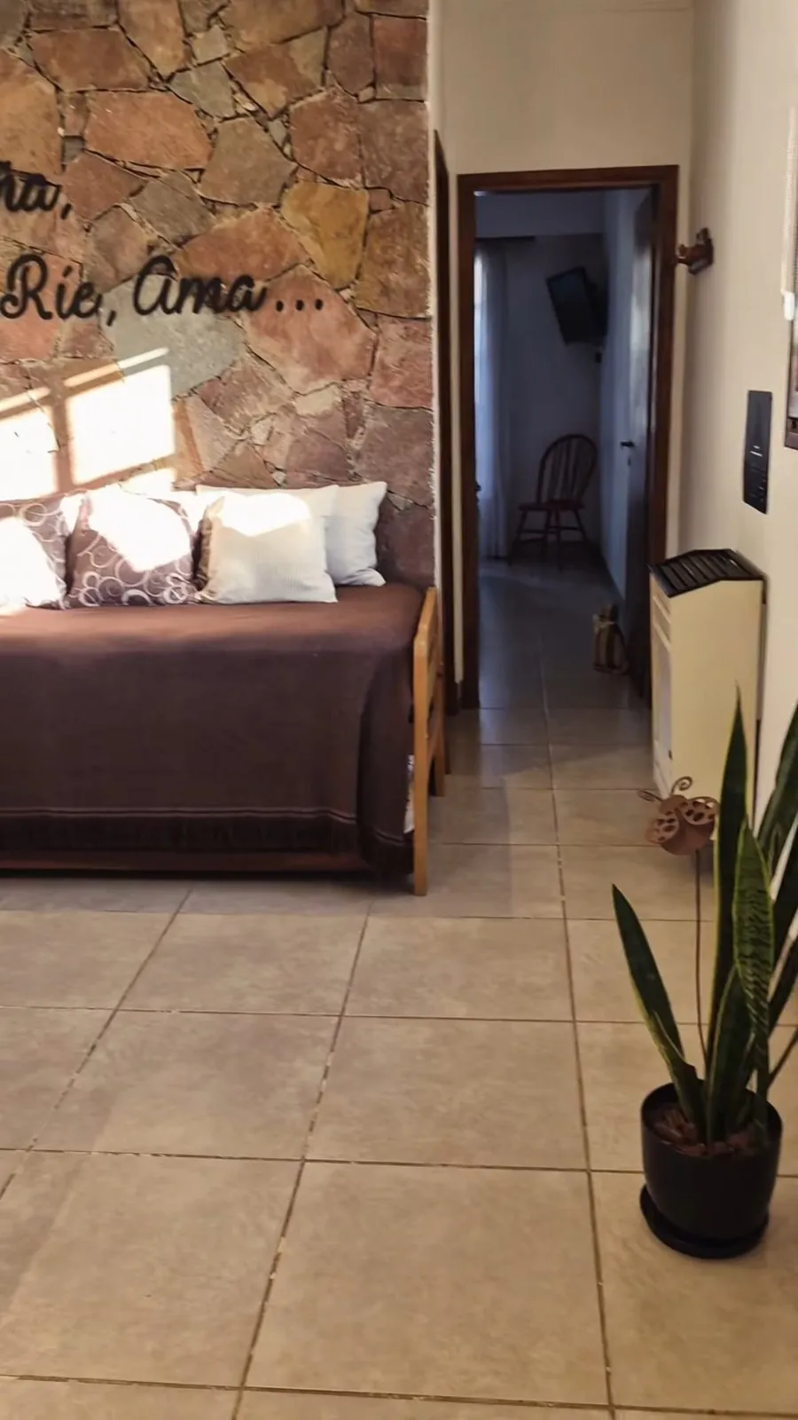 Living con pared de piedra y pasillo